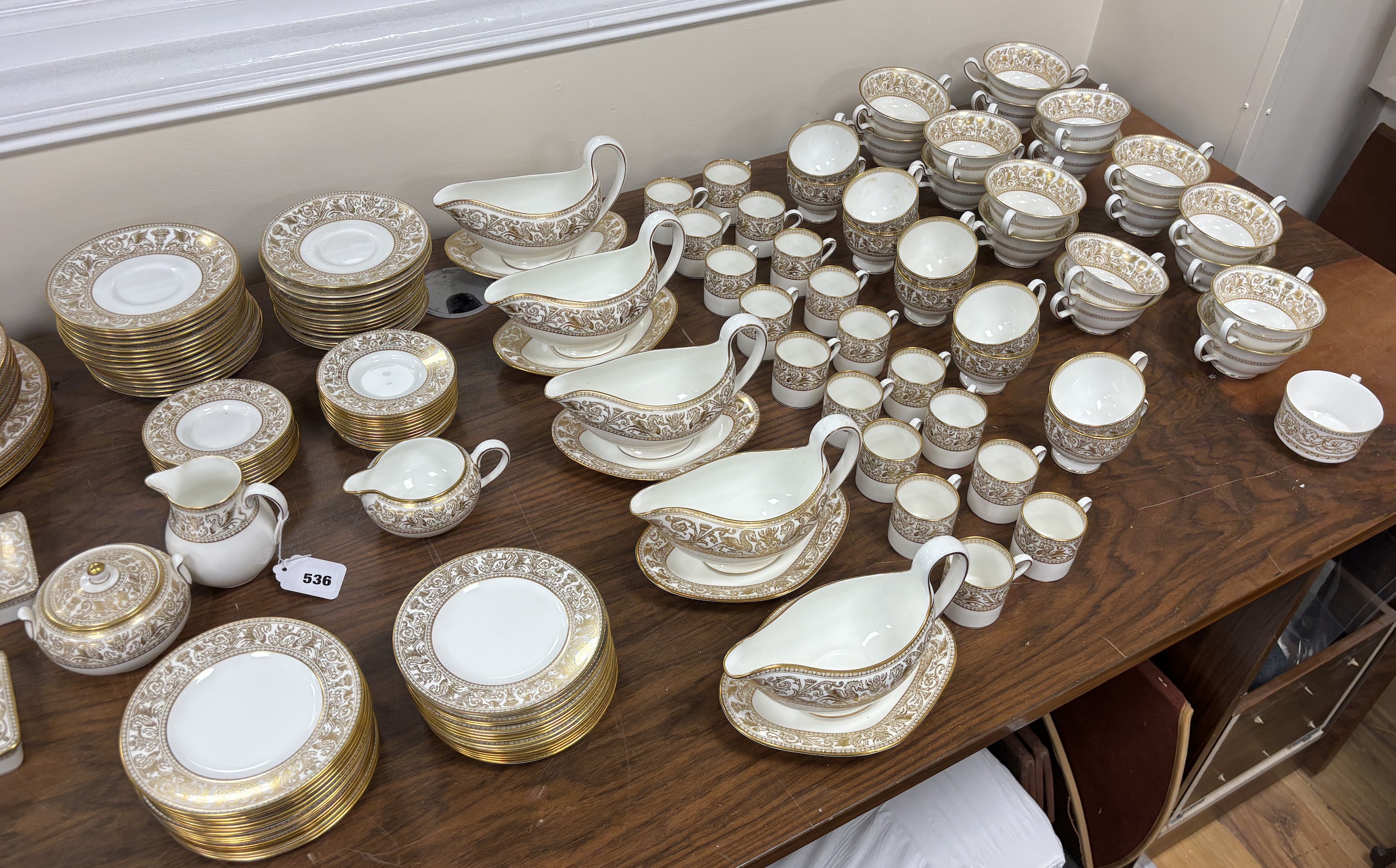 An extensive Wedgwood Gold Florentine dinner service, including 26 dinner plates, 50 side plates, 18 soup bowls with 16 saucers, 6 tea cups and 4 saucers, 6 bowls, 6 large cheese plates, 5 gravy boats and 3 saucers, 3 ve